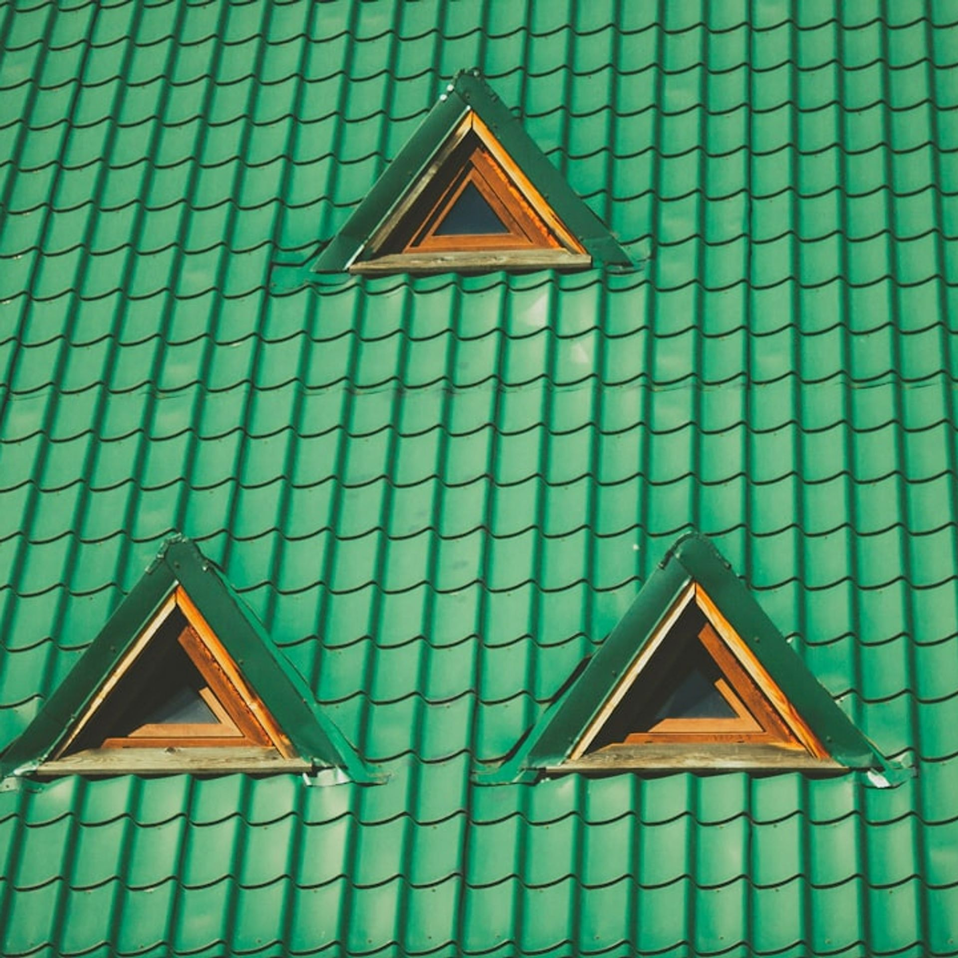 Green tiled roof with symmetrical triangular dormer windows and wooden frames, ideal for urban and rural architecture. Green tiled roof with symmetrical triangular dormer windows and wooden frames, ideal for urban and rural architecture.