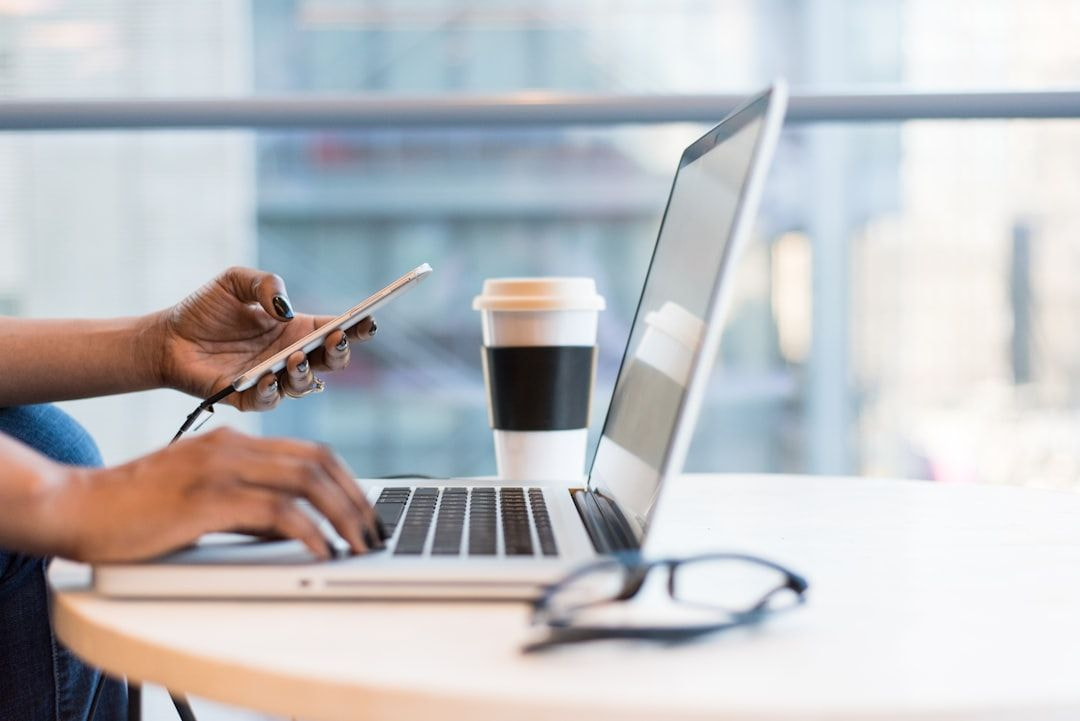 Multitasking with tech: Laptop, smartphone, and coffee in a modern workspace.