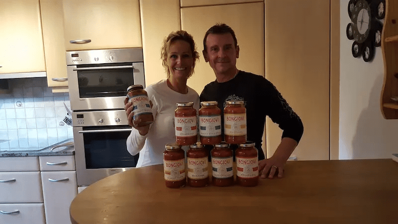 „Zwei Personen präsentieren verschiedene Bongiovi Pastasaucen in einer Küche – Vielfalt der Marke.“ „Zwei Personen präsentieren verschiedene Bongiovi Pastasaucen in einer Küche – Vielfalt der Marke.“