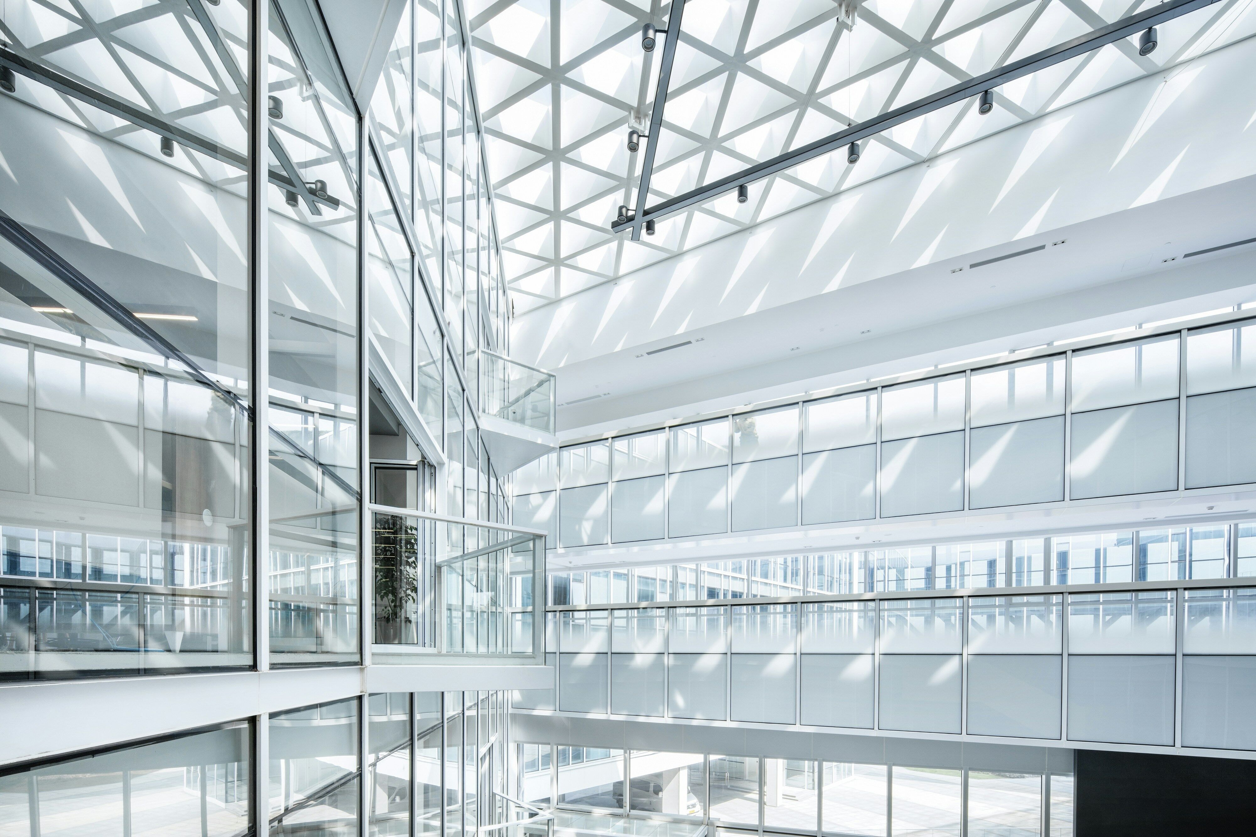 Moderno edificio per uffici luminoso con pareti in vetro e design geometrico del soffitto.